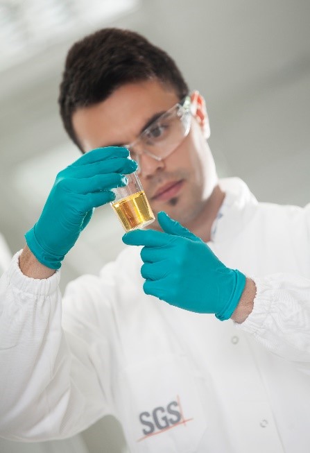 Umut Arslan inspects a flask of oil in the lab.
